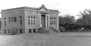 black and white photo of brick building with gabled entrance and stone steps to front entrance